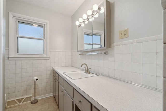 bathroom featuring tile patterned flooring, vanity, a wainscoted wall, tile walls, and visible vents