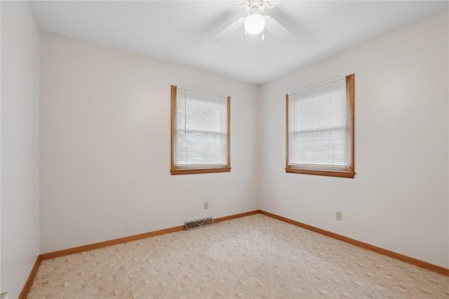 empty room featuring baseboards, a ceiling fan, light colored carpet, and visible vents