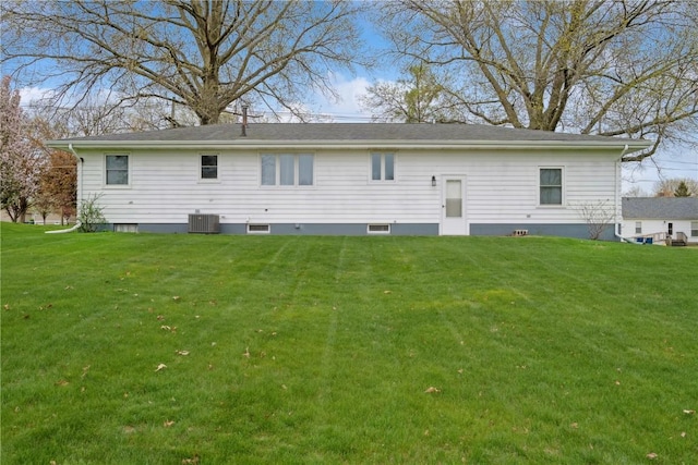 back of property with central AC unit and a yard