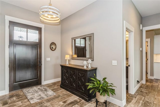 entryway with baseboards, wood finished floors, and a chandelier