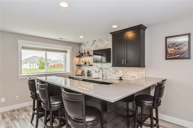 bar featuring visible vents, baseboards, indoor wet bar, tasteful backsplash, and a sink