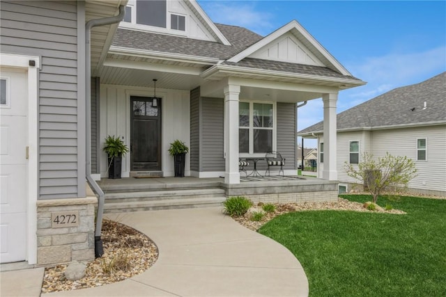entrance to property featuring a lawn, board and batten siding, a shingled roof, and a porch