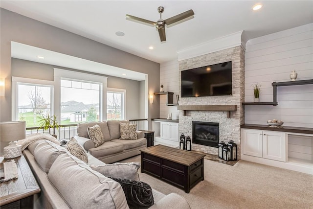 living room featuring ceiling fan, recessed lighting, a stone fireplace, and light colored carpet