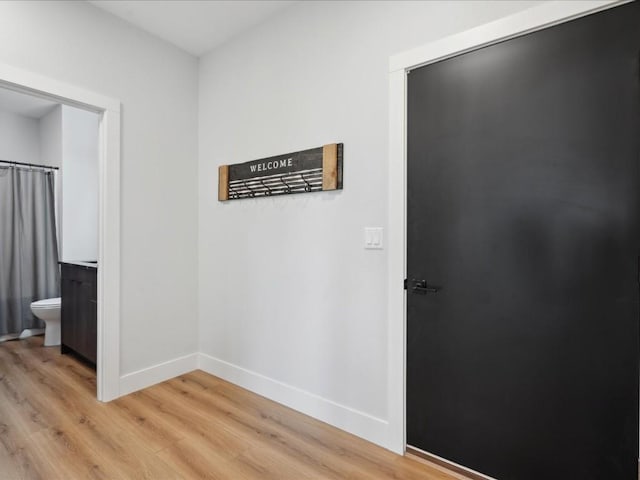 corridor with baseboards and light wood finished floors