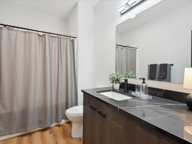 bathroom with toilet, curtained shower, wood finished floors, and vanity