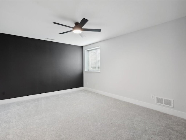 spare room with carpet floors, ceiling fan, baseboards, and visible vents