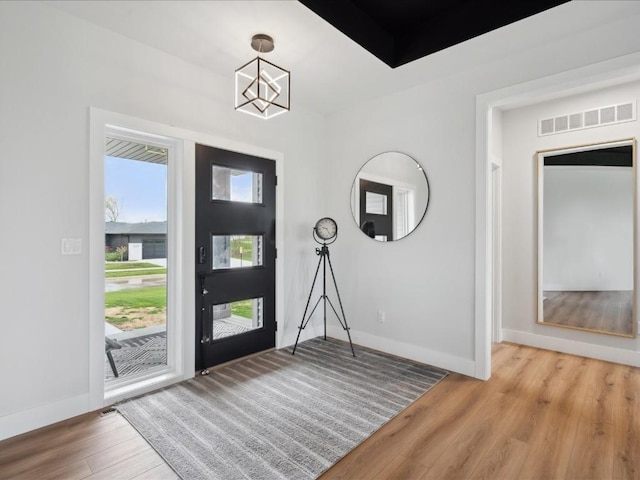 foyer with visible vents, baseboards, a chandelier, and light wood-type flooring