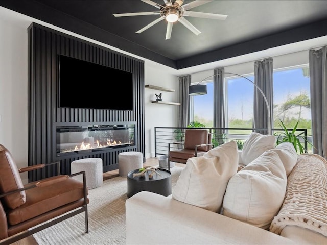 living room with plenty of natural light, a glass covered fireplace, ceiling fan, and wood finished floors