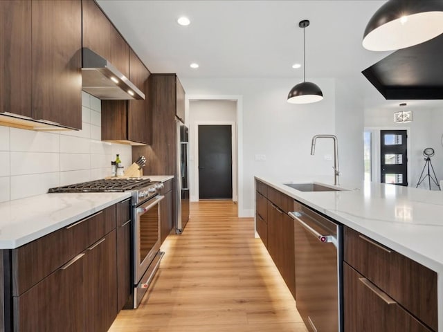 kitchen featuring a sink, appliances with stainless steel finishes, range hood, and modern cabinets