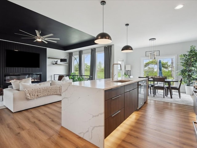 kitchen with open floor plan, modern cabinets, a sink, light wood-style flooring, and dishwasher