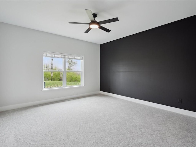 carpeted empty room featuring baseboards and a ceiling fan