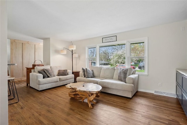 living room featuring baseboards, visible vents, and wood finished floors