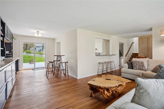 living area with baseboards, stairs, and wood finished floors