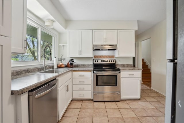 kitchen featuring a sink, stainless steel appliances, white cabinetry, light tile patterned floors, and under cabinet range hood