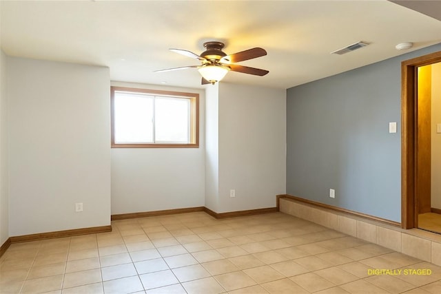 empty room with light tile patterned floors, baseboards, a ceiling fan, and visible vents