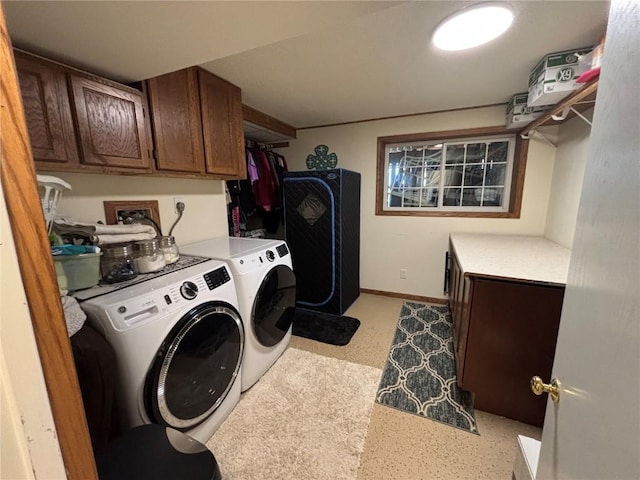 clothes washing area with baseboards, cabinet space, and washer and dryer