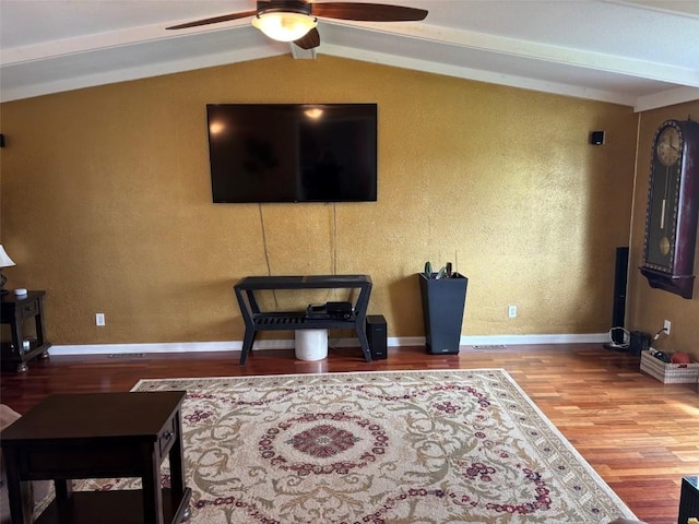 living room featuring ceiling fan, vaulted ceiling with beams, a textured wall, and wood finished floors