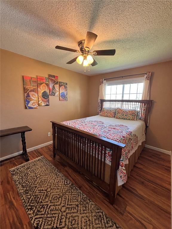 bedroom featuring baseboards, a ceiling fan, a textured ceiling, and wood finished floors