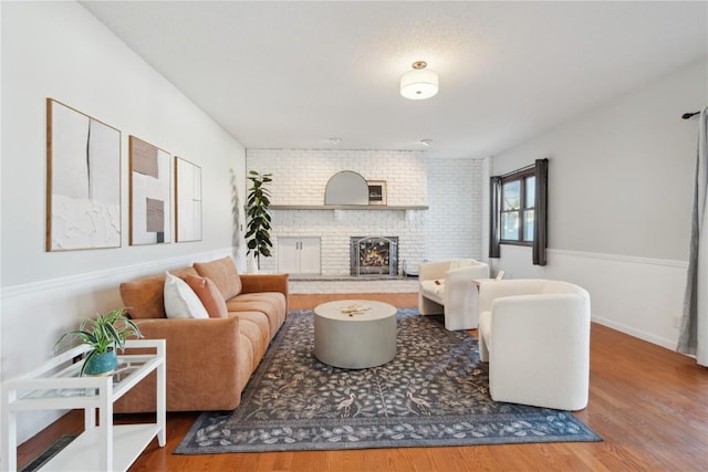 living room with a brick fireplace and wood finished floors