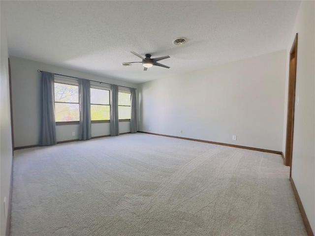 spare room featuring a ceiling fan, light colored carpet, visible vents, and baseboards