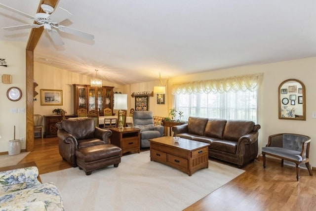 living area featuring vaulted ceiling, ceiling fan with notable chandelier, and light wood-type flooring