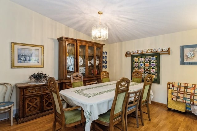 dining area with an inviting chandelier, light wood-style floors, and baseboards