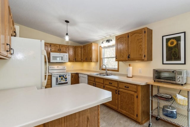 kitchen featuring a sink, light countertops, a toaster, a peninsula, and white appliances