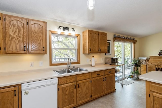kitchen featuring a sink, light countertops, brown cabinets, and dishwasher