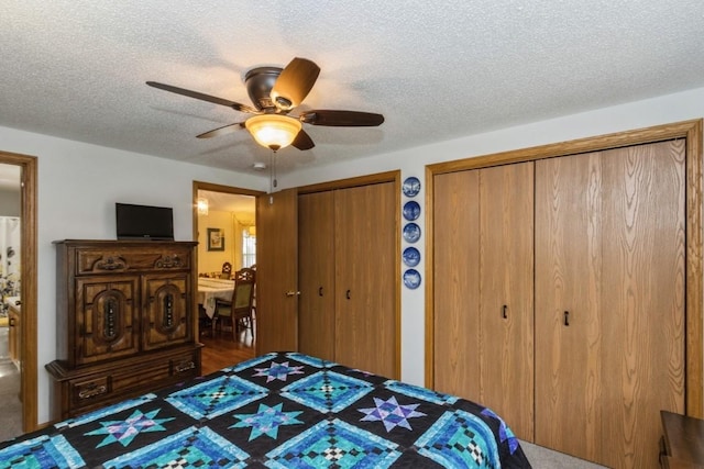 bedroom featuring a textured ceiling, multiple closets, and a ceiling fan