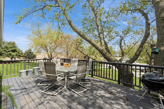 wooden deck featuring grilling area, a lawn, and outdoor dining space