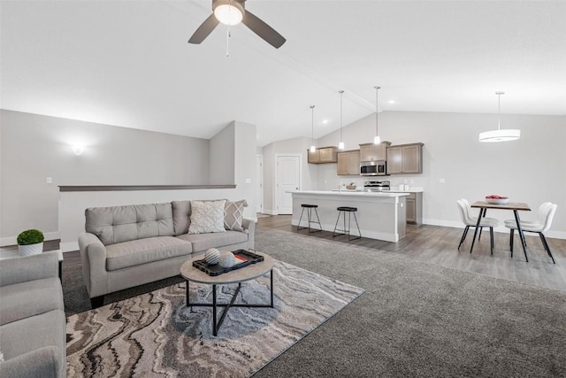 carpeted living room with baseboards, ceiling fan, wood finished floors, and vaulted ceiling