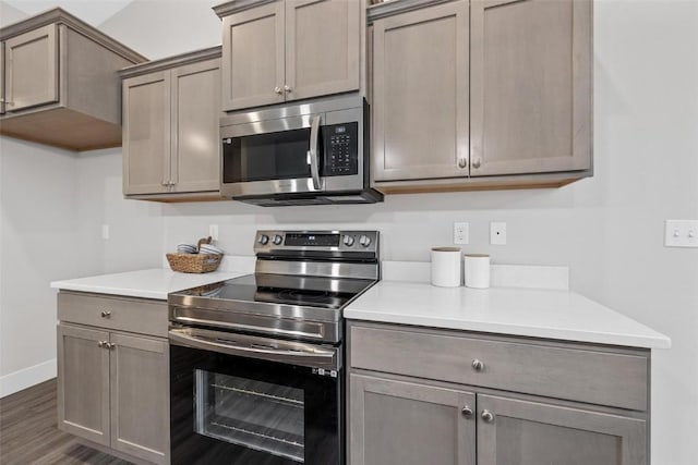 kitchen with baseboards, light countertops, appliances with stainless steel finishes, and dark wood-style floors
