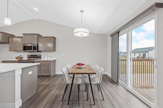 dining space featuring vaulted ceiling with beams, light wood-style floors, and baseboards