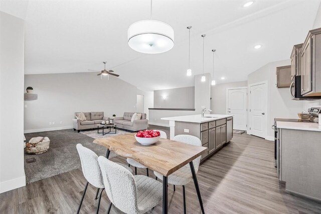 dining area featuring a ceiling fan, baseboards, vaulted ceiling, and wood finished floors
