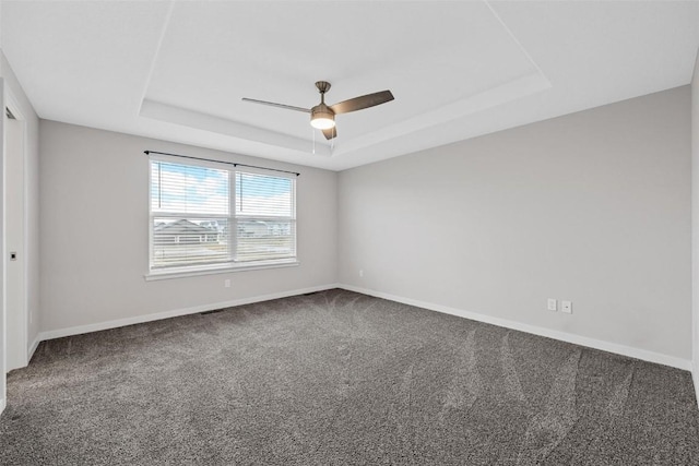 unfurnished room featuring ceiling fan, carpet floors, baseboards, a tray ceiling, and visible vents