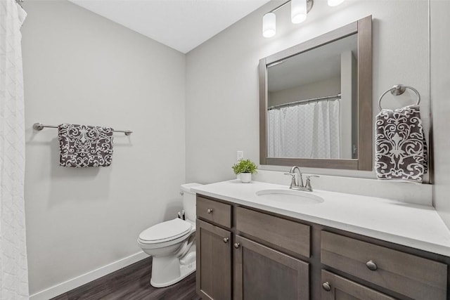 bathroom featuring toilet, baseboards, wood finished floors, and vanity