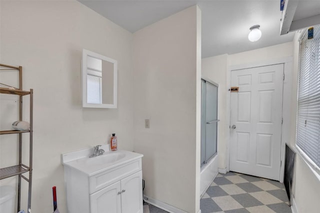 bathroom with a healthy amount of sunlight, vanity, bath / shower combo with glass door, tile patterned floors, and toilet