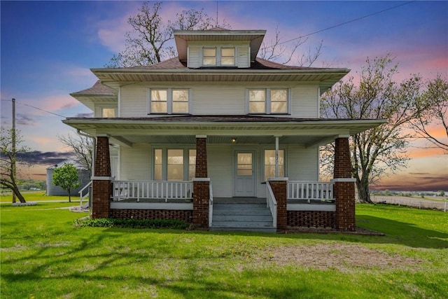 american foursquare style home featuring a lawn and covered porch
