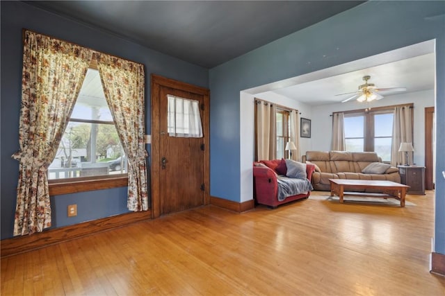 living room with baseboards, ceiling fan, and wood finished floors