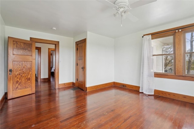 spare room with wood-type flooring, a ceiling fan, baseboards, and visible vents
