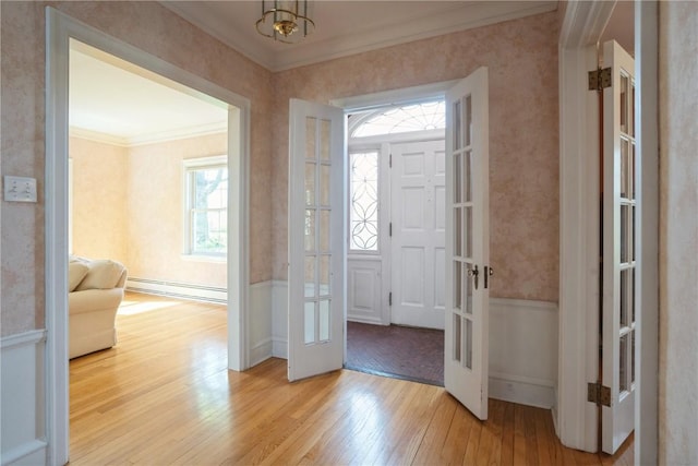 entrance foyer featuring ornamental molding, light wood-type flooring, french doors, and a baseboard radiator