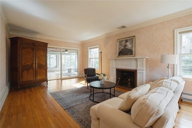 living area featuring crown molding, a fireplace, hardwood / wood-style floors, and visible vents