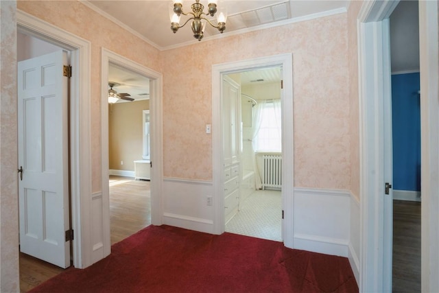 hall featuring crown molding, wainscoting, a chandelier, radiator heating unit, and wallpapered walls