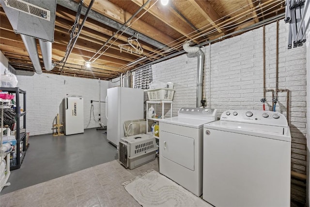 laundry room with laundry area, brick wall, and washer and dryer
