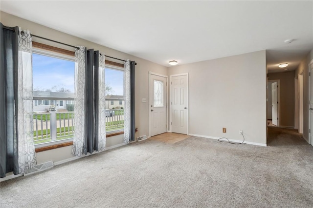 unfurnished living room featuring baseboards, visible vents, and carpet