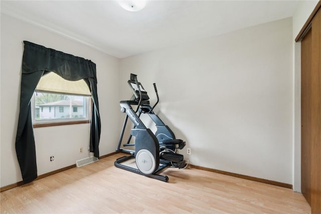 exercise area with baseboards, visible vents, and light wood-style floors