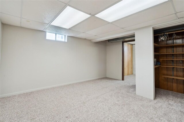 basement with carpet flooring, baseboards, and a drop ceiling