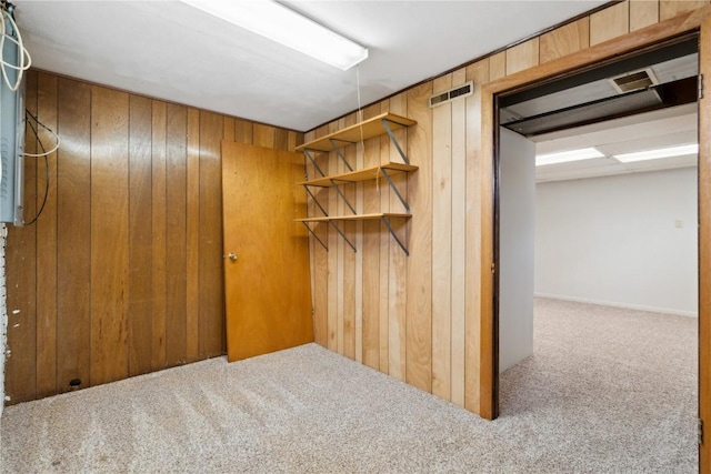 finished basement with visible vents, wood walls, and carpet
