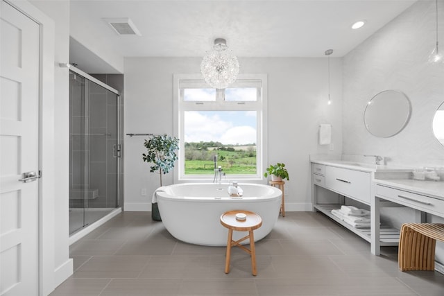full bath featuring visible vents, a shower stall, vanity, a chandelier, and a soaking tub
