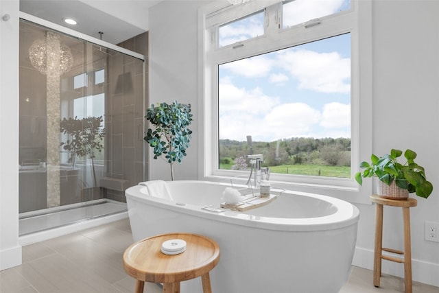 bathroom featuring a stall shower, a notable chandelier, and a soaking tub